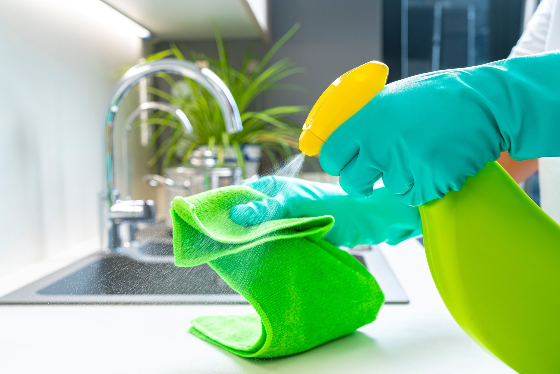 Cleaning  kitchen counter with spray bottled soap and microfiber towel